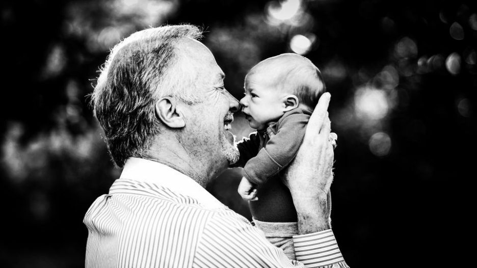 grandfather holding up baby