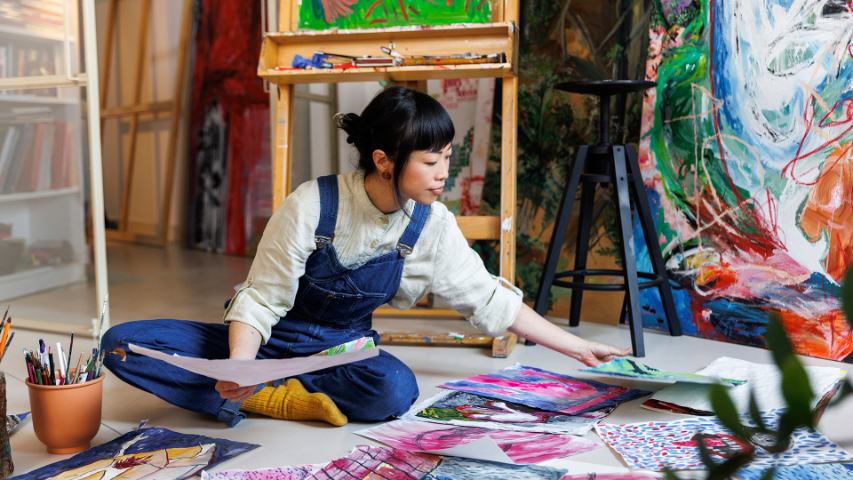 Female artist arranging paintings on floor