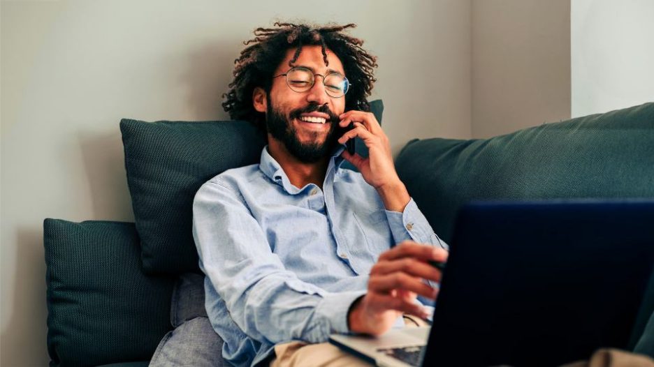 man on his mobile phone and his laptop while working from home