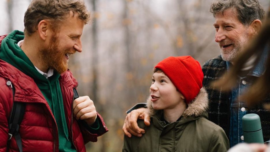 three generations of men having fun during hike in woods