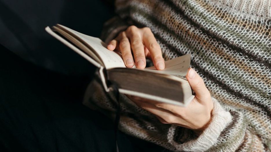 close-up of persons hands turning the pages of a book